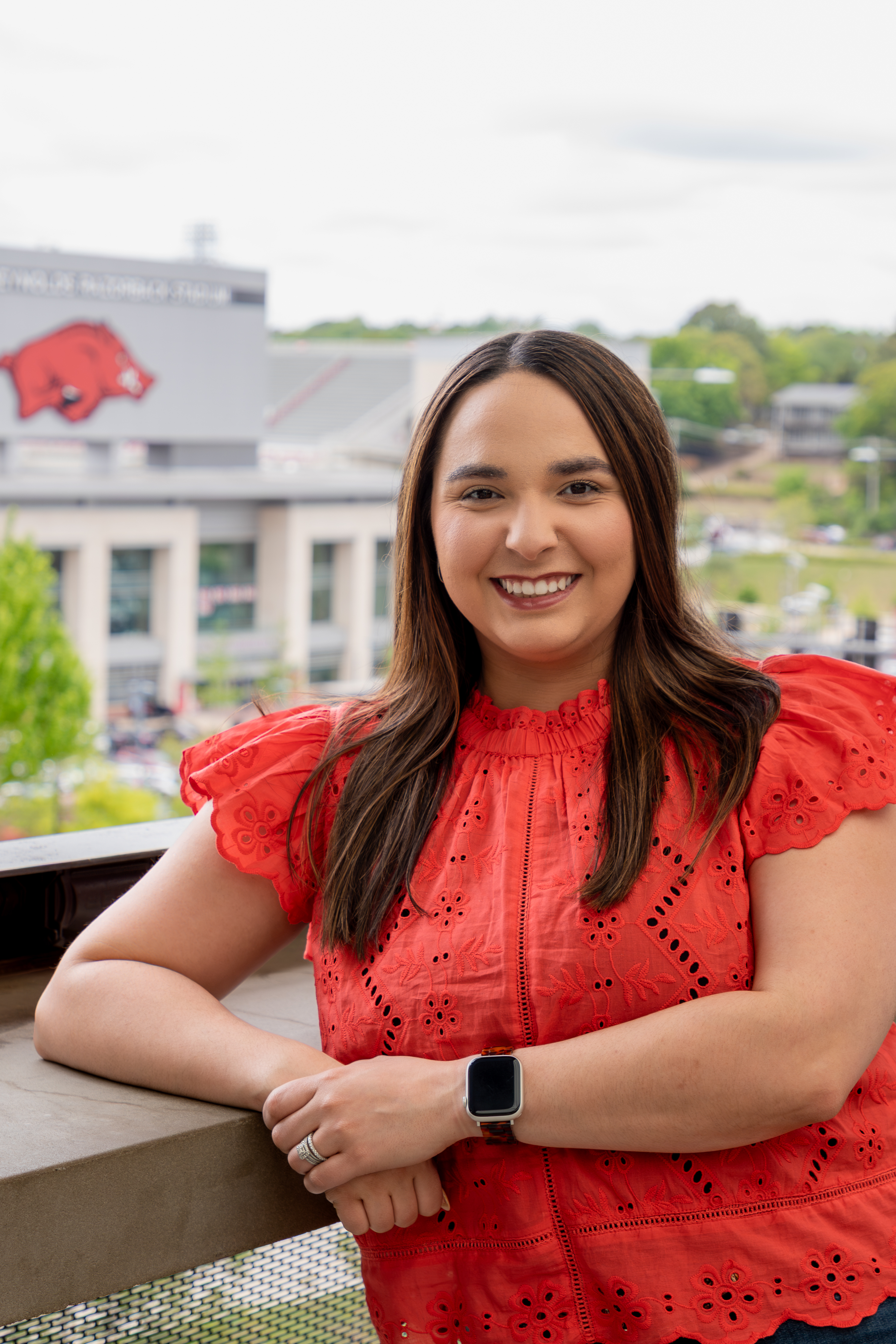 Brunette woman wearing a red shirt standing with razorback stadium in background