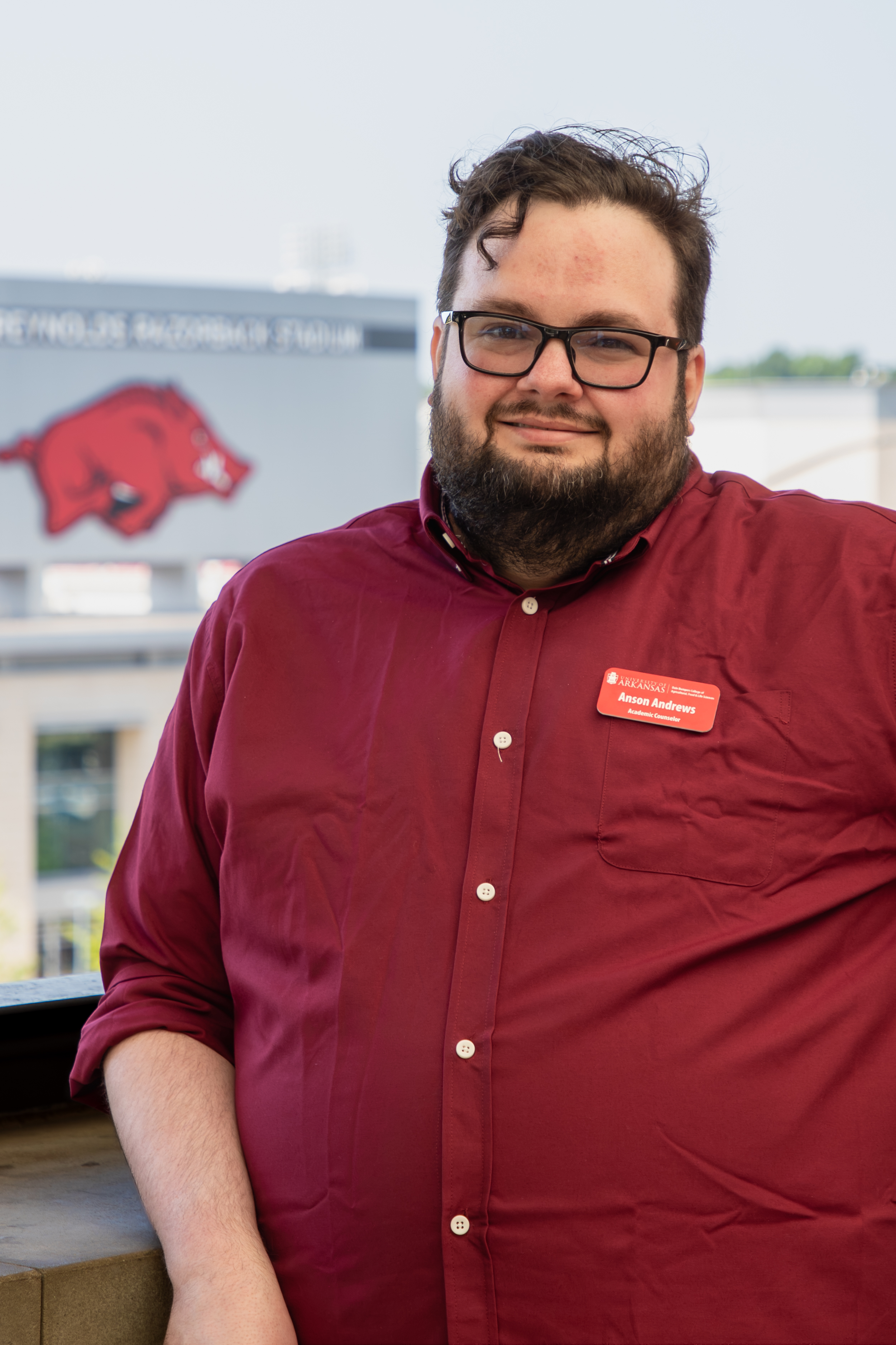 Headshot of Anson Andrews, a man with a beard and glasses wearing a red button-down shirt.