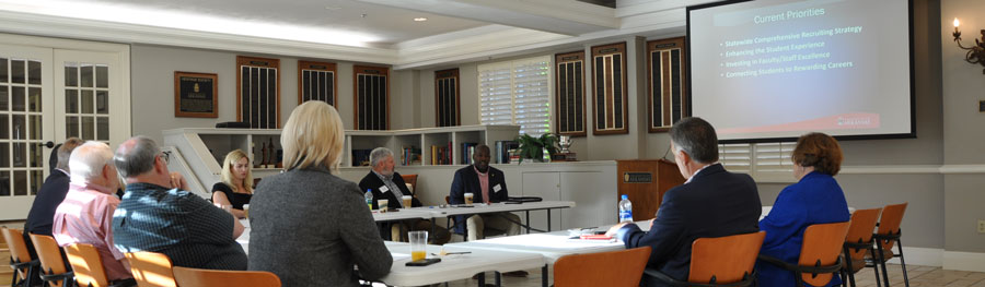 The AFLS Dean's Partnership Council fall 2018 meeting. The group is sitting around a table while the Dean gives a presentation.